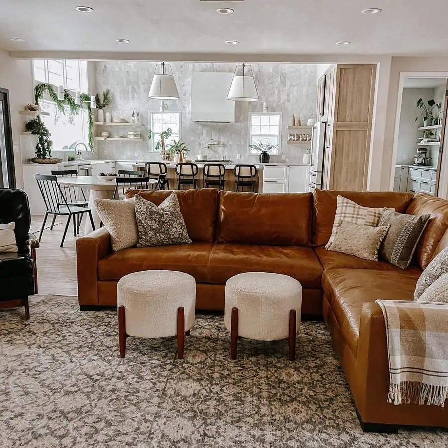 Large leather sectional in a neutral color living room with kitchen in the background.