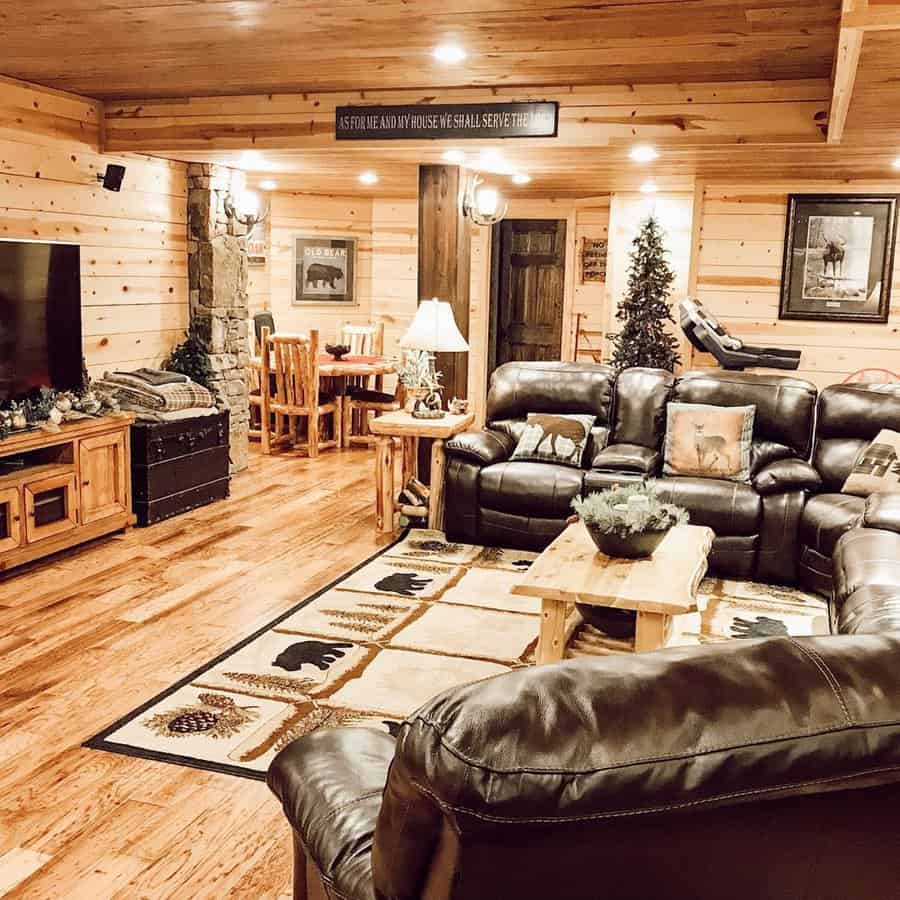 Warm and cozy cabin-style living room featuring dark leather sofas, wooden furniture, and rustic decor accents.