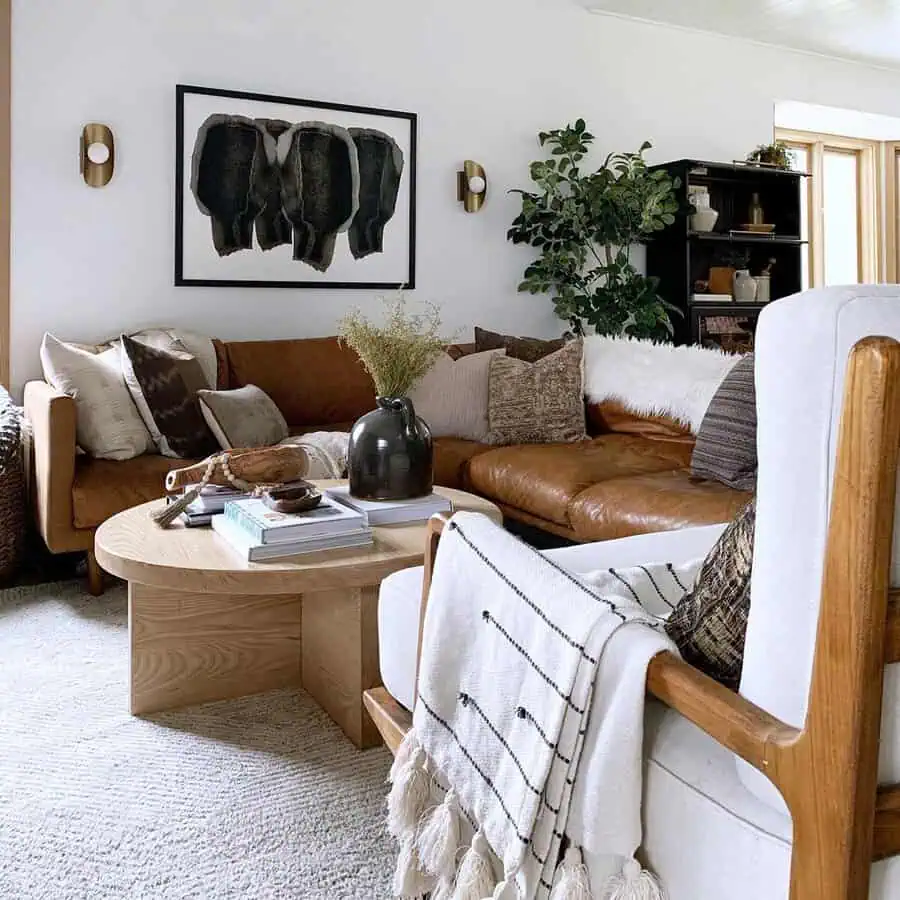 Modern living room with brown leather sectional, abstract wall art, and a round wooden coffee table.