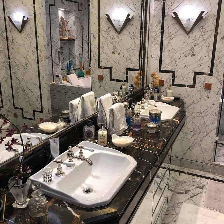 Elegant Art Deco bathroom with marble walls, black countertop, and large vanity mirrors.