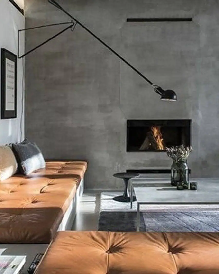 Mid-century modern living room with leather tufted seating, concrete walls, and minimalist fireplace.