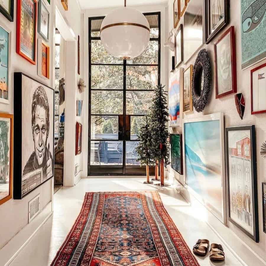 A modern hallway filled with eclectic artwork, framed by a large window and a colorful rug, adds personality and warmth to the space.