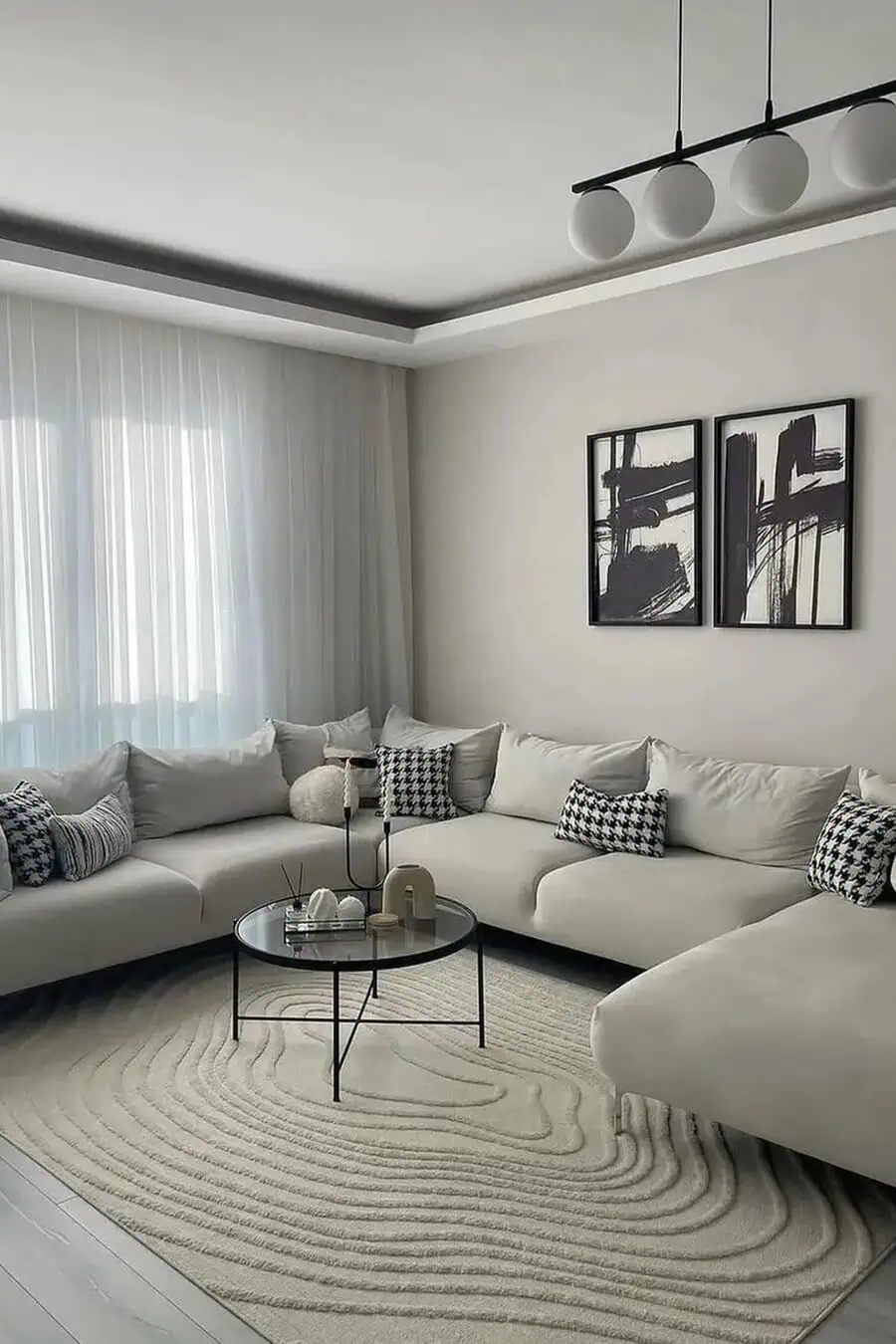 Modern living room with a white sectional, abstract art, round glass table, and textured rug.