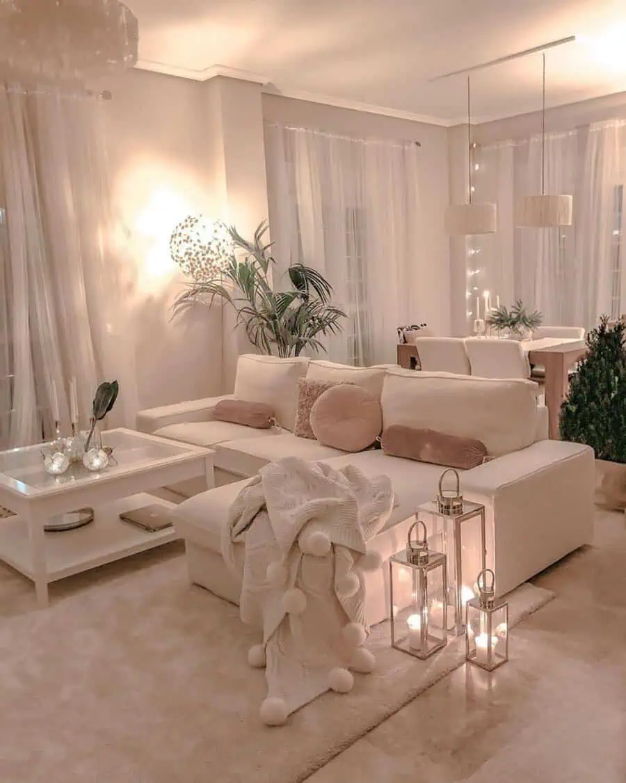 Cozy living room with soft lighting, white furniture, candles, and light beige decor accents.