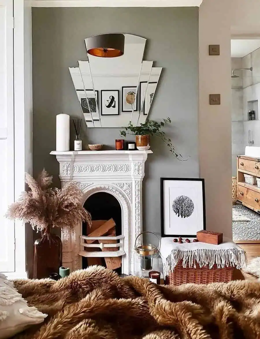 Cozy bedroom with an ornate white fireplace, decorative mirror, wall art, and natural decor accents.