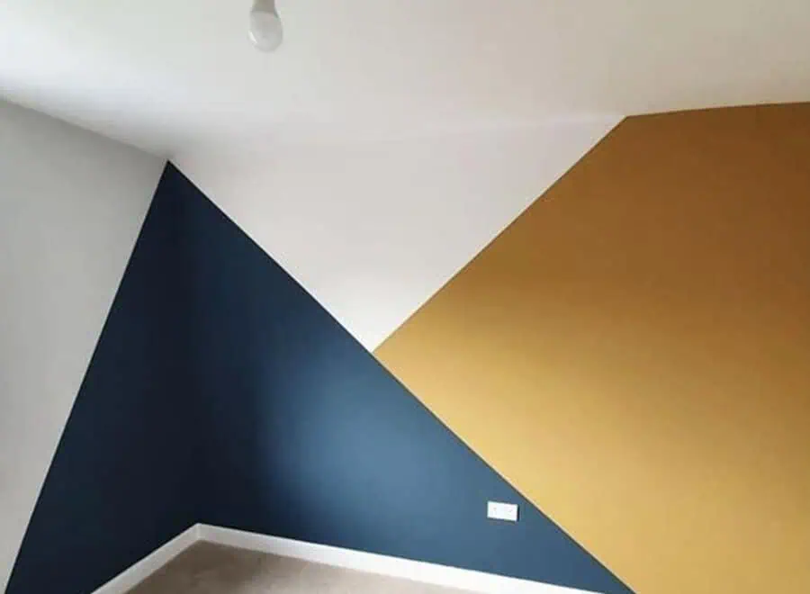 Geometric accent wall design with navy, mustard, and white colors in a modern room.