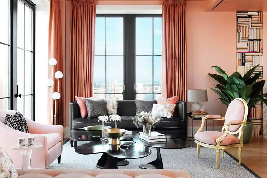 Chic living room with pink accents, large windows, and a mix of modern and vintage furniture.