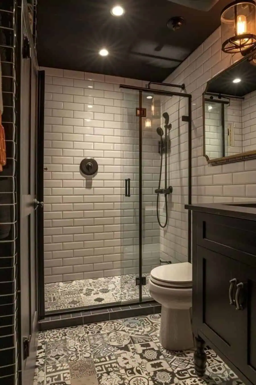 Small Art Deco bathroom with subway tile walls, glass shower, patterned tile floor, and black vanity.