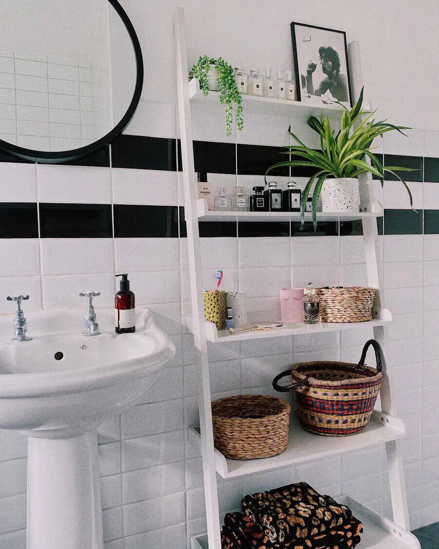 Small bathroom with pedestal sink, white shelves, woven baskets, and potted plant decor.