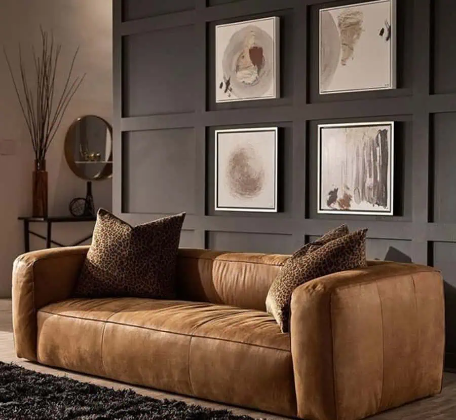 Small living room with brown leather couch, leopard print pillows, and modern wall art.