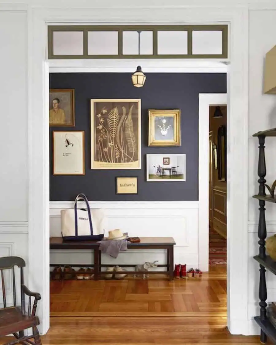 Vintage-inspired gallery wall in hallway with botanical prints, bench, and wooden floors.