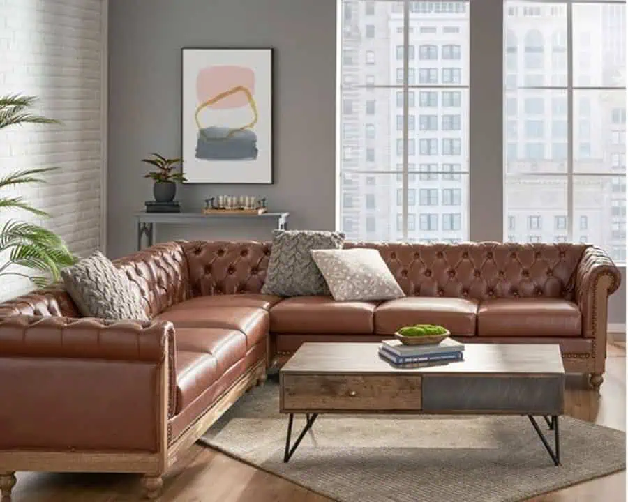 Modern living room with vintage brown leather sectional, abstract wall art, and large windows.