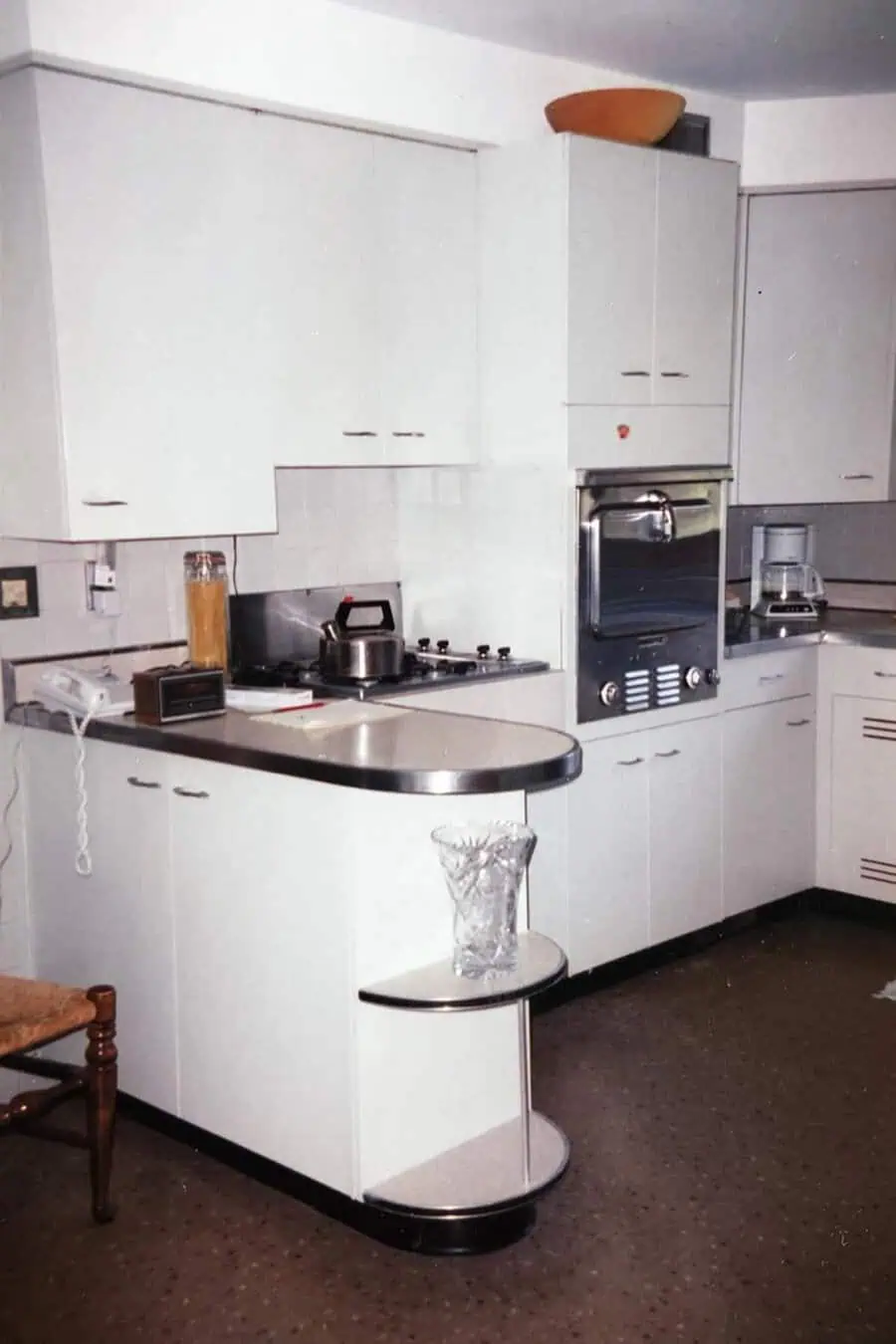 1950s kitchen with white cabinets, Formica countertop, and retro built-in appliances.