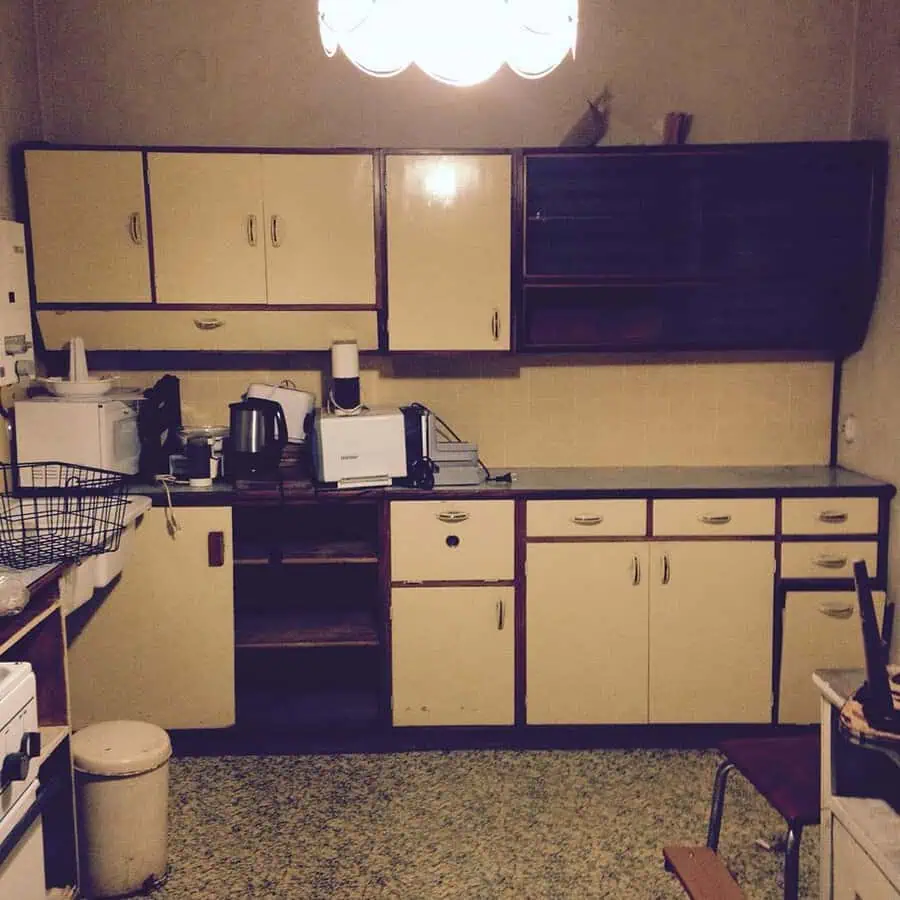 1950s kitchen with cream cabinets, wood trim, and retro pendant lighting.