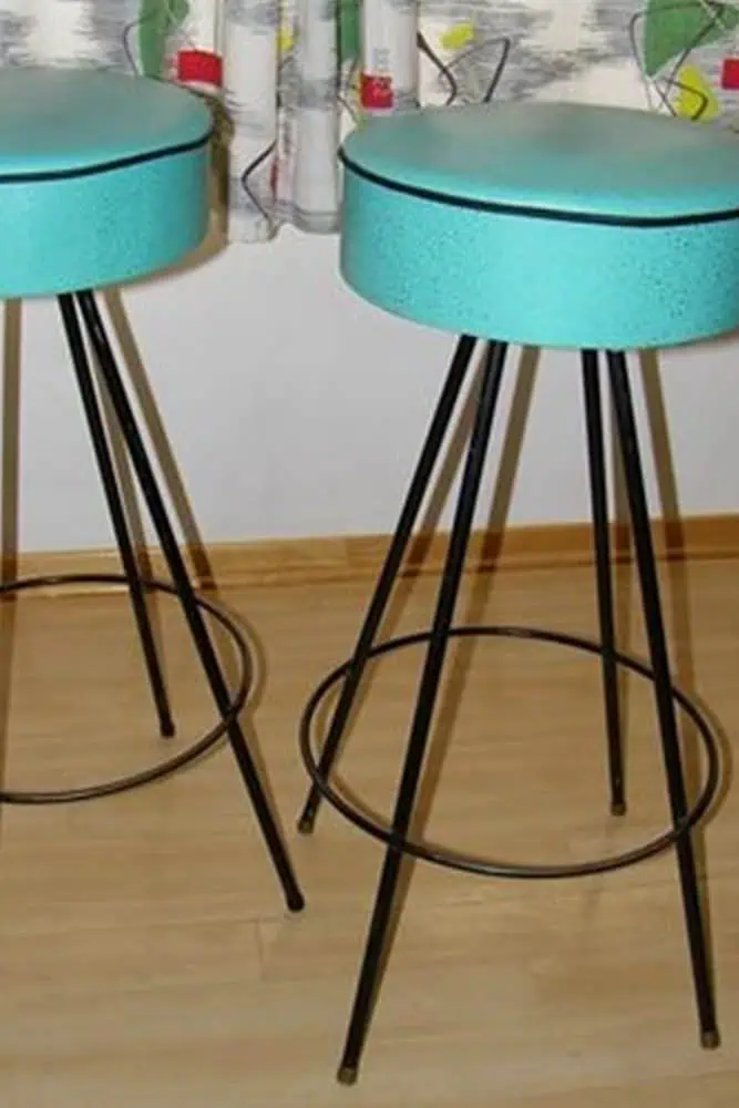 1950s turquoise bar stools with black metal legs and retro patterned curtains.