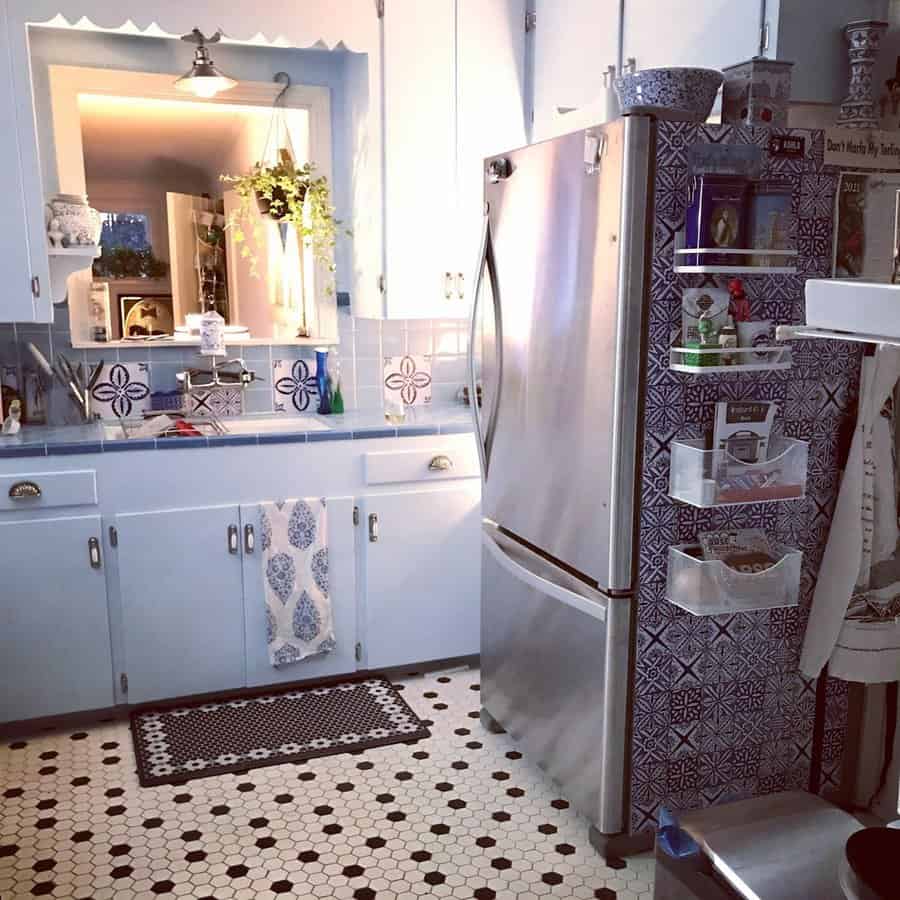 1950s kitchen with light blue cabinets, patterned tiles, and stainless steel refrigerator.