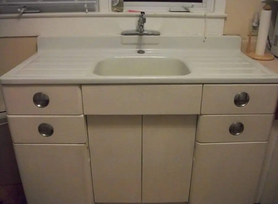 1950s metal sink cabinet with integrated drainboard and chrome handles.