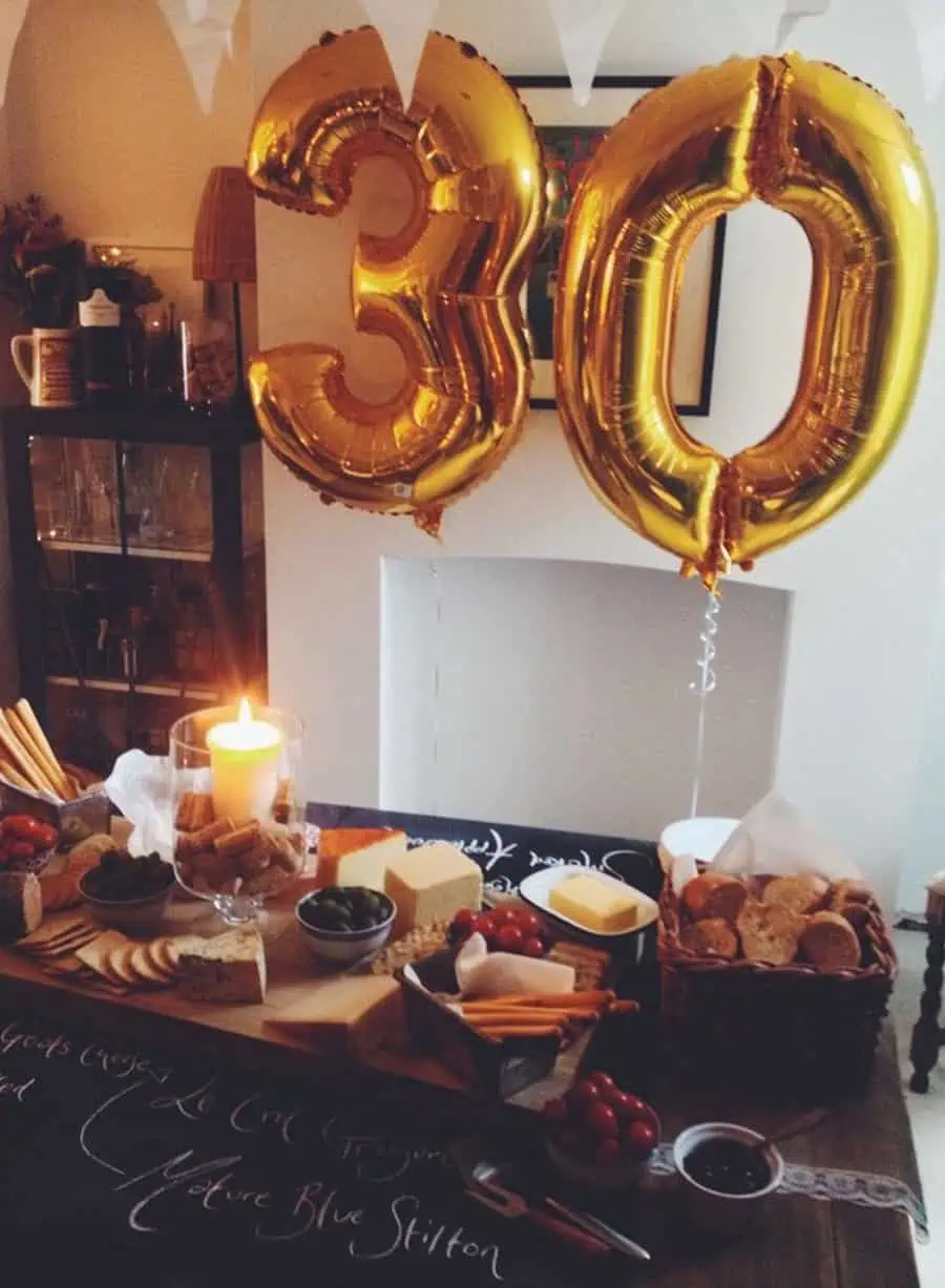 Gold "30" balloons with a cozy cheese and charcuterie spread for a birthday celebration.