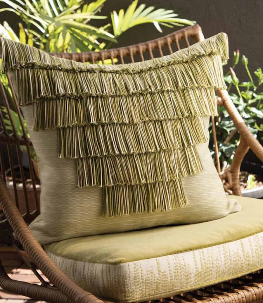 Eclectic outdoor chair with green tassel pillow and matching cushioned seat.