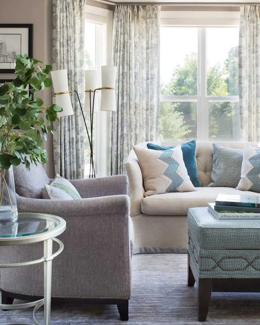 Elegant living room with neutral furniture, teal and aqua accents, large windows, and patterned curtains.