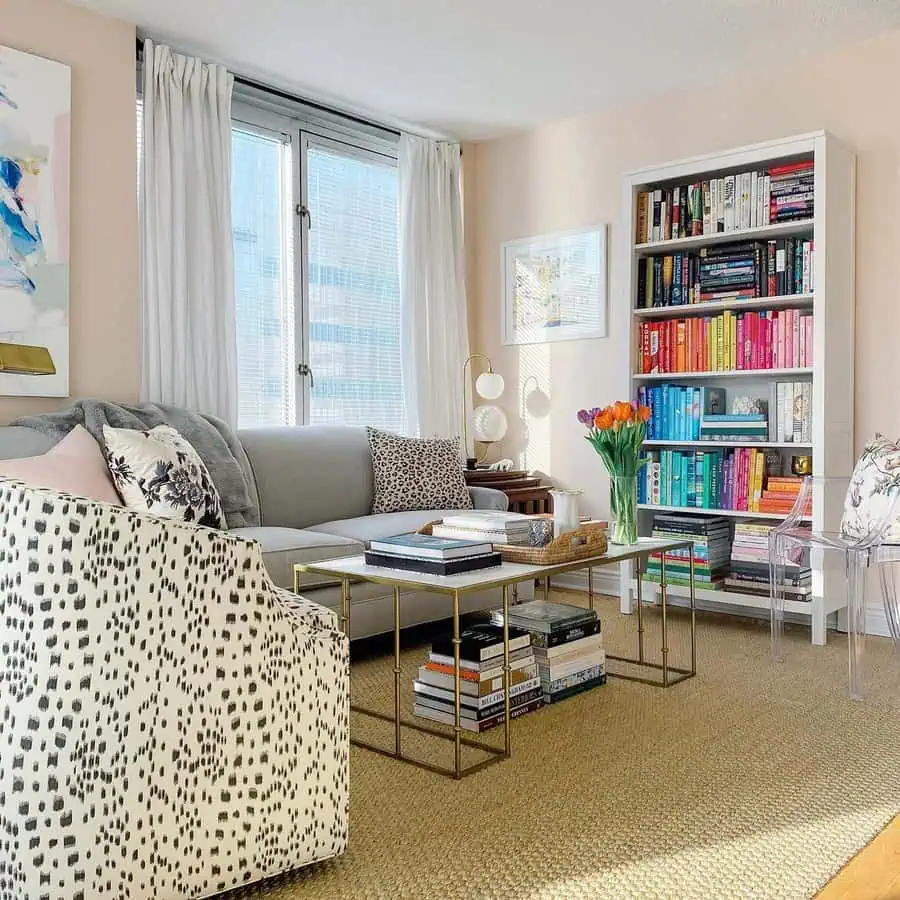 Bright living room with colorful bookshelf, floral decor, modern furniture, and natural lighting.