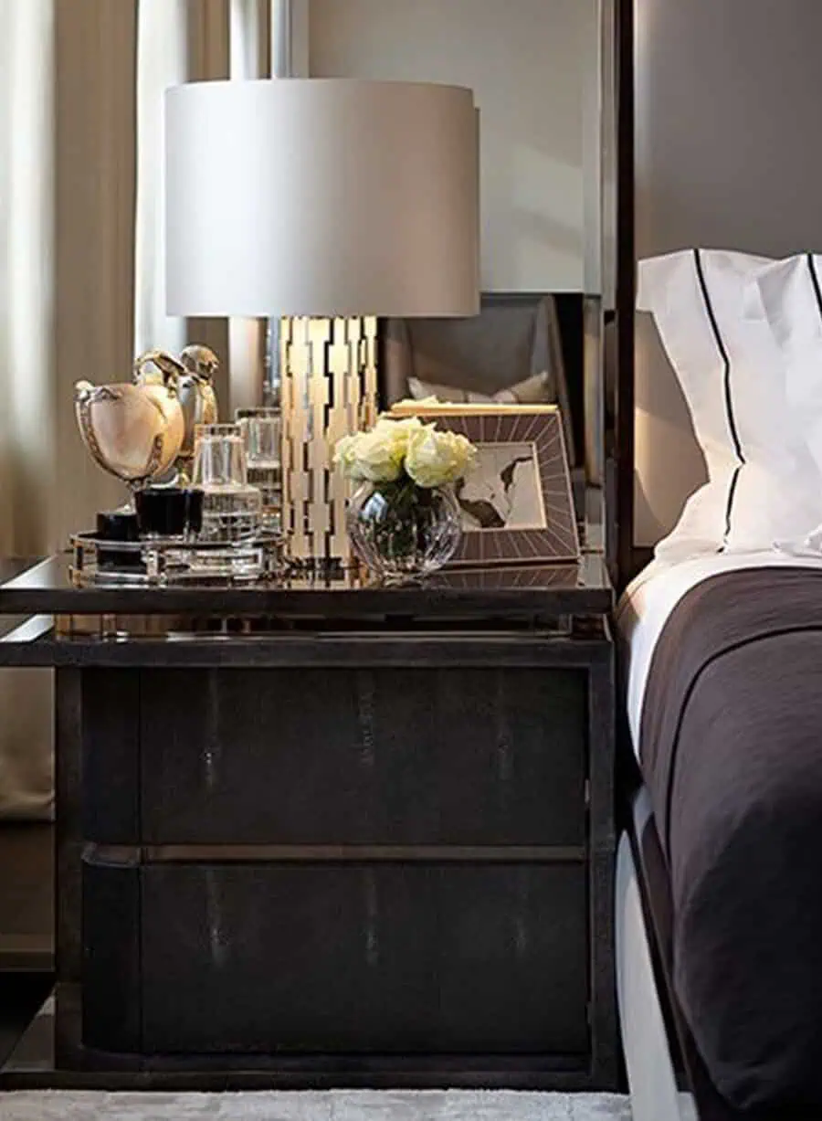 Sleek bedside table with metallic accents, fresh roses, and elegant decor for a modern bedroom.