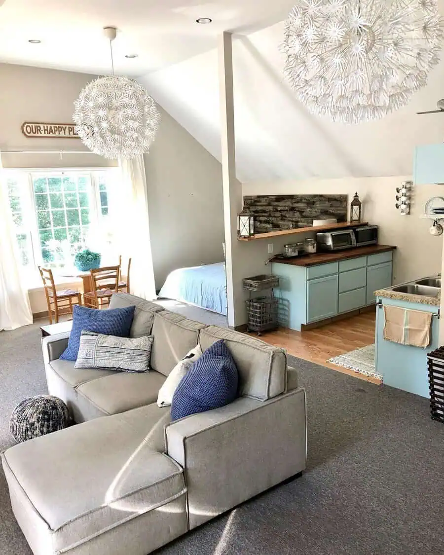 Bright studio apartment with cozy seating, blue cabinetry, and functional compact furniture.