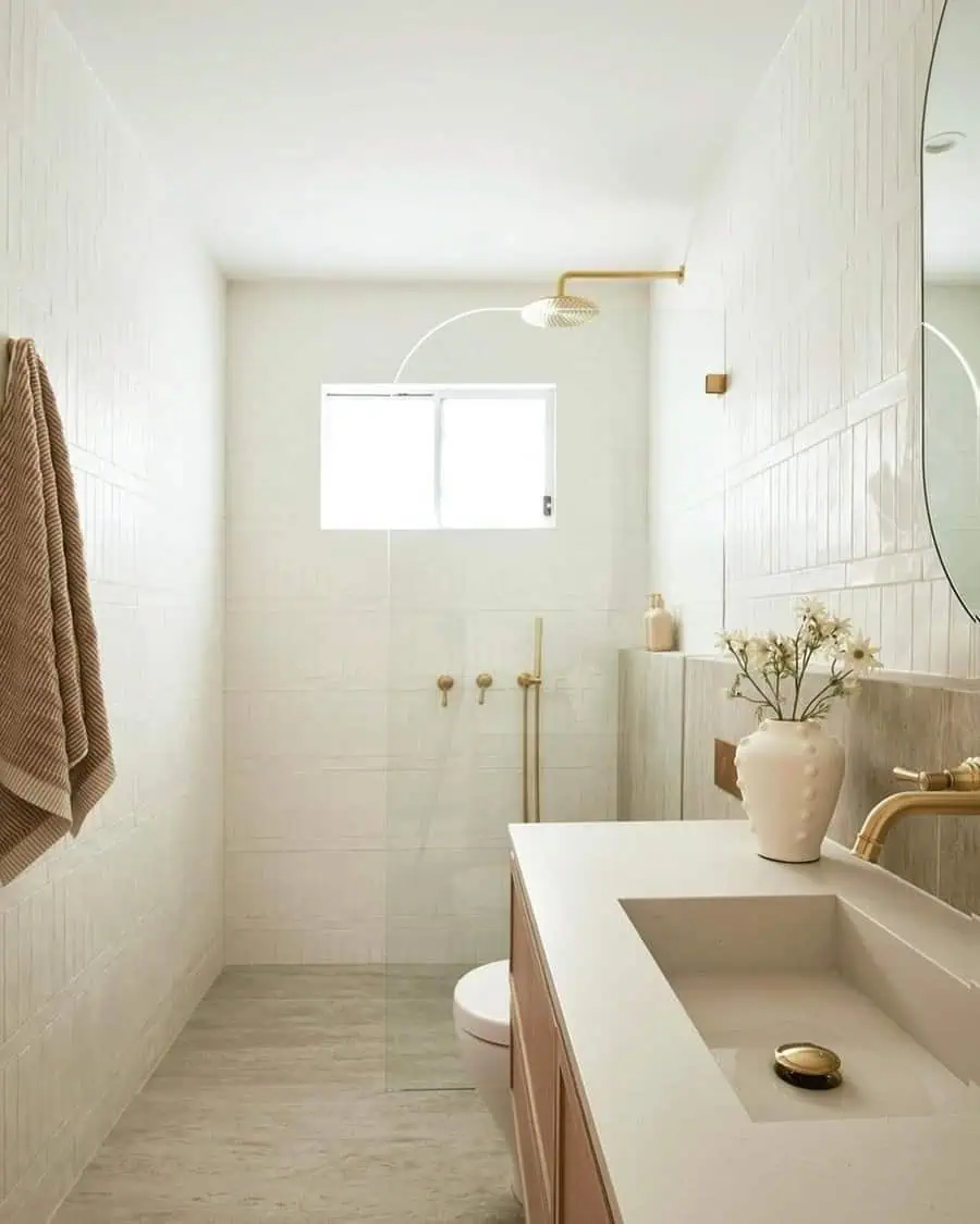 Small luxury bathroom with gold fixtures, walk-in shower, vase decor, and minimalist design.