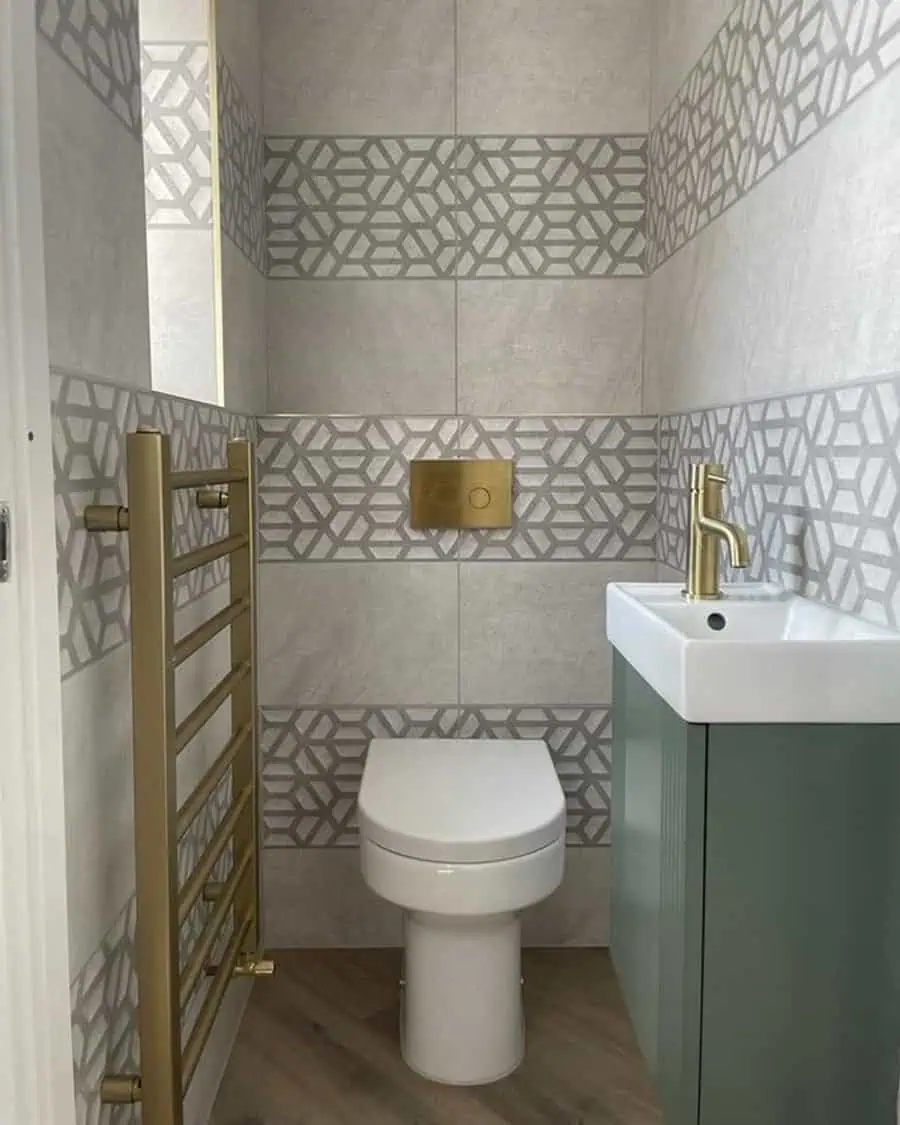 Small bathroom with modern geometric tiles, gold fixtures, and a compact wall-mounted sink.