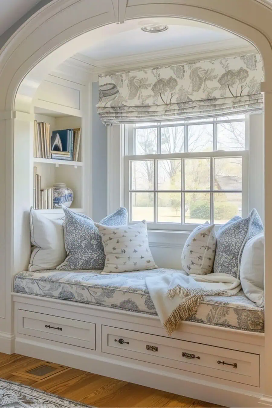 Built-in window seat with floral cushions, cozy pillows, and a view of a sunny backyard.