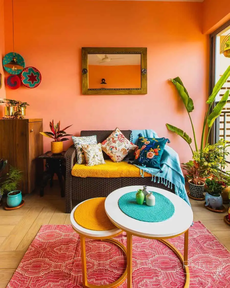 Colorful eclectic space with vibrant cushions, plants, and a pink patterned rug.