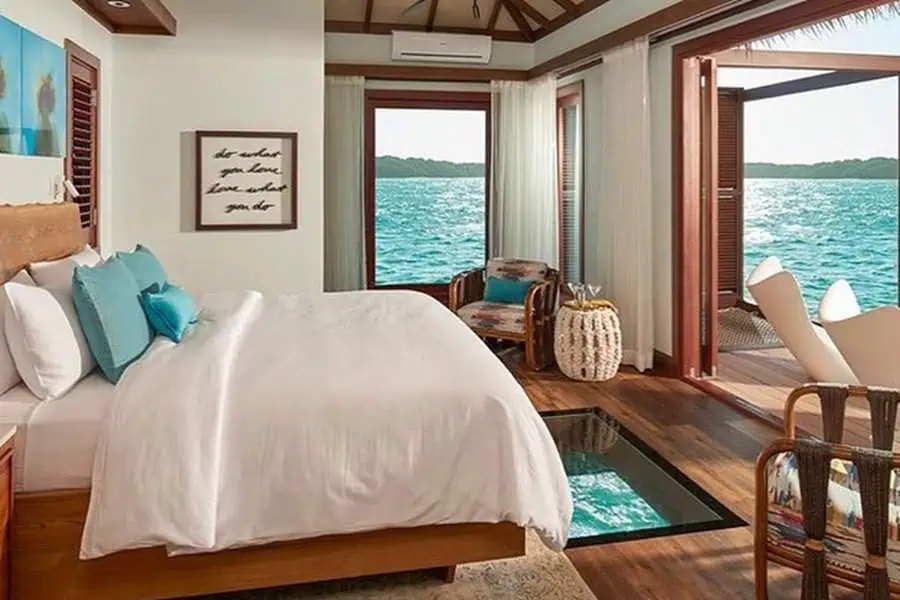 Bedroom with ocean view, glass floor feature, and tropical decor for a romantic ambiance.