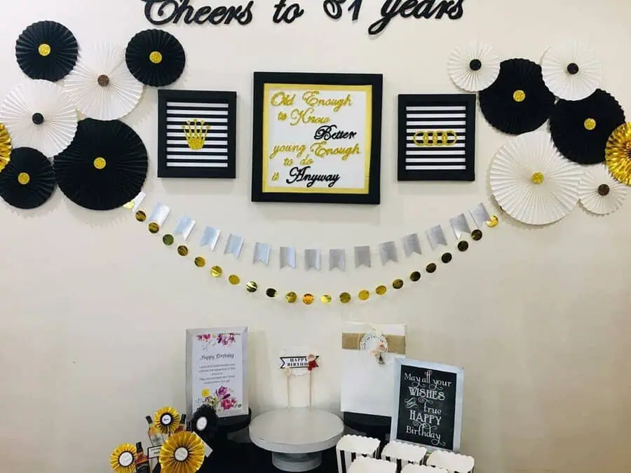 Black, white, and gold-themed birthday decor with banners, framed quotes, and creative wall accents.