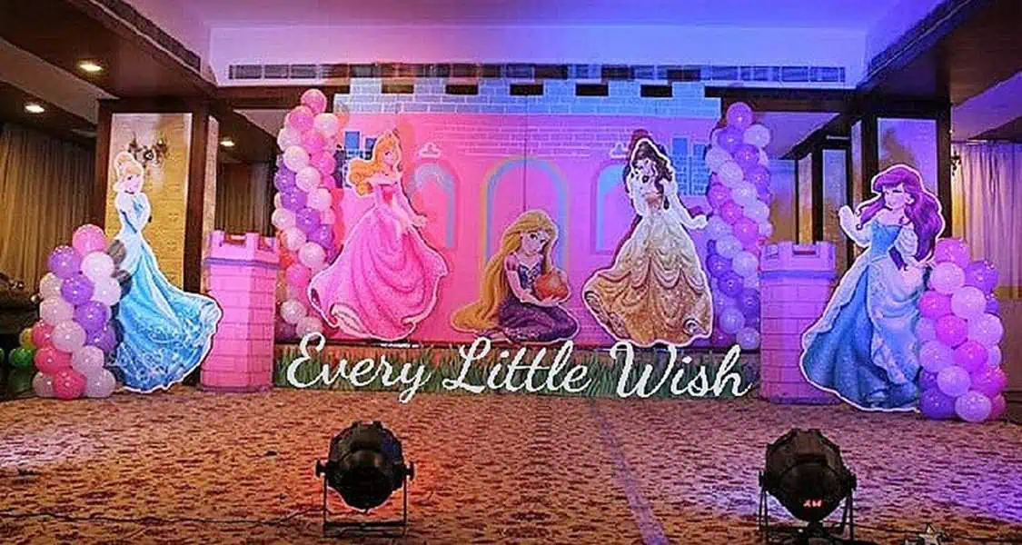 Disney princess-themed birthday party with character cutouts, balloon decor, and lighted sign.