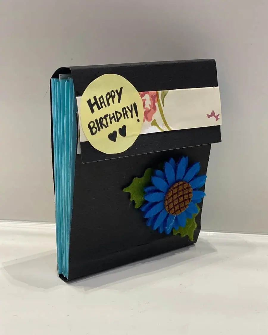 Handmade birthday card with a blue flower decoration and "Happy Birthday" message.