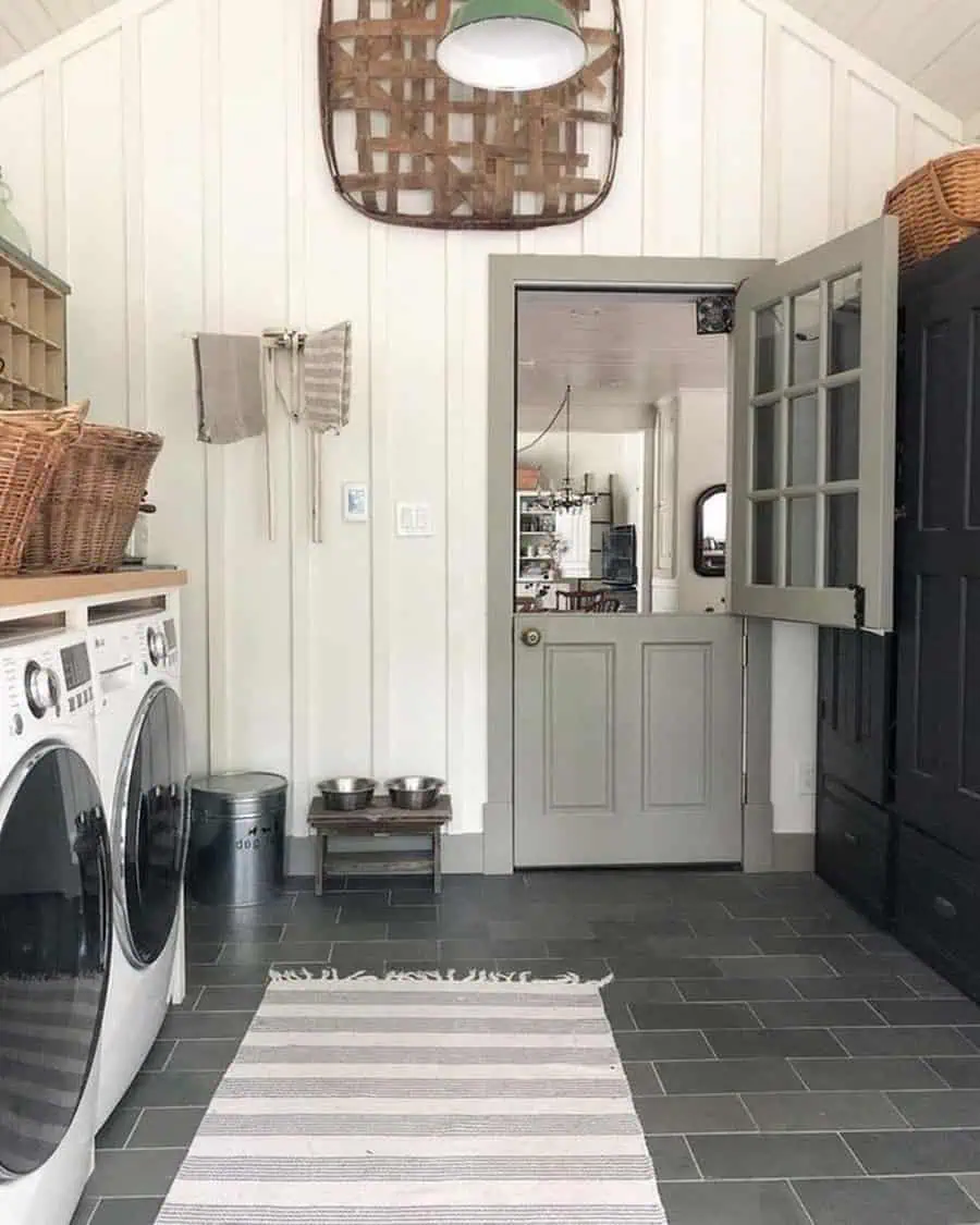 Cozy laundry room with gray Dutch door, white panel walls, and modern washer-dryer units.