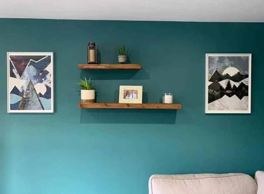 Teal living room with a feature wall and floating shelves for decor accents.