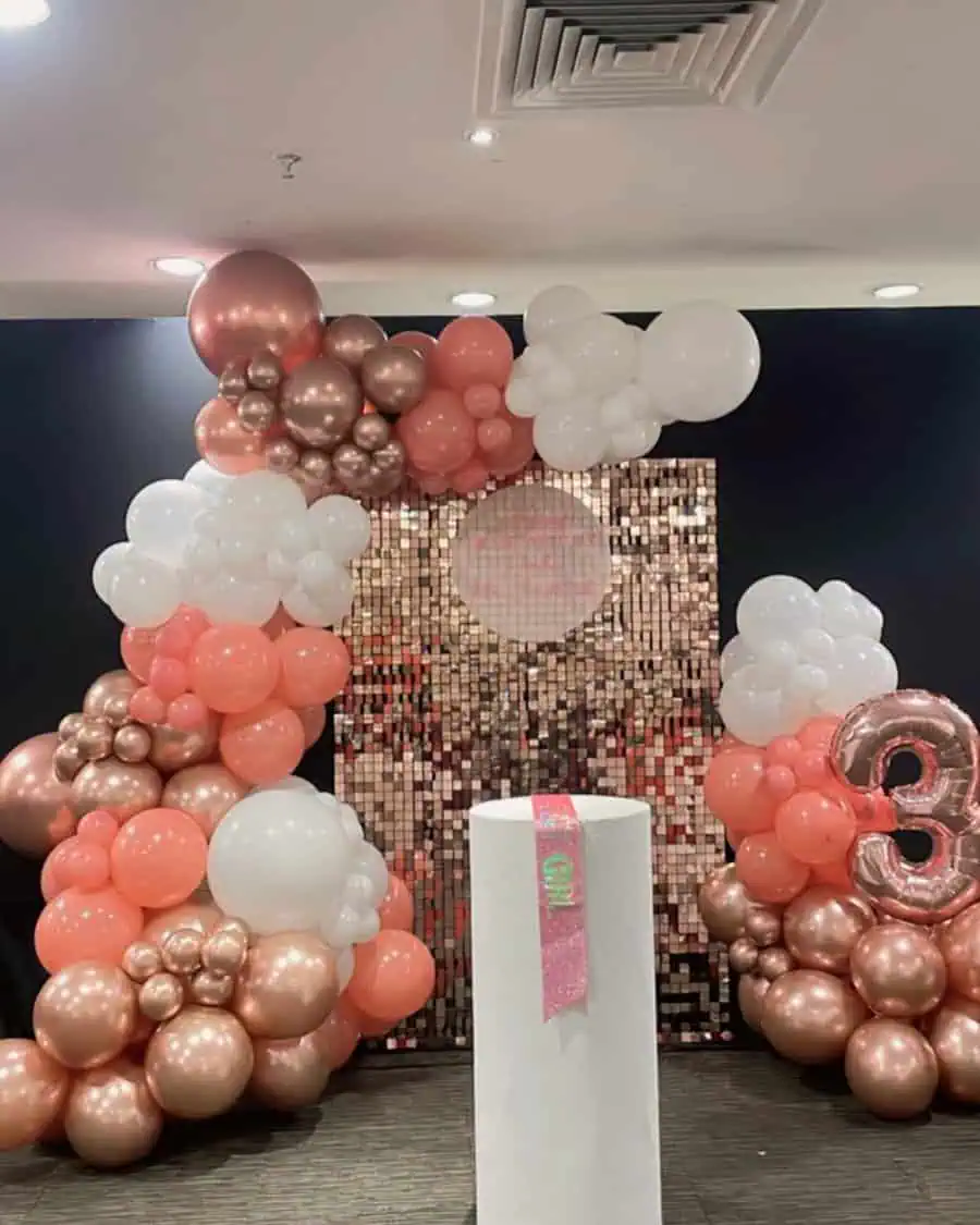 Surprise birthday setup with rose gold and white balloons, sequin backdrop, and number 3 decoration.