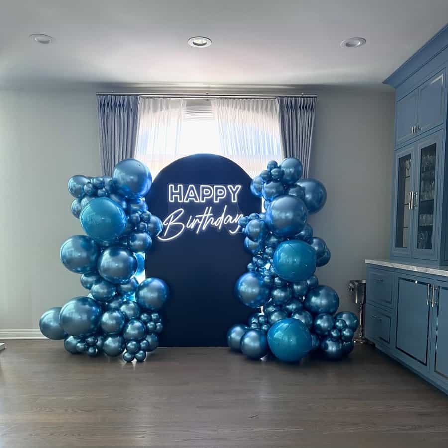 Friend's surprise birthday setup with blue metallic balloons and a neon "Happy Birthday" sign.