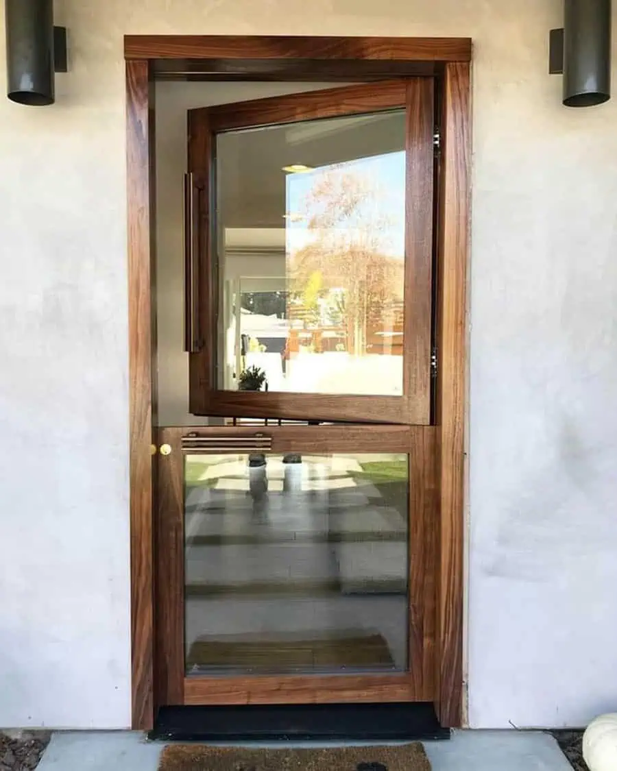 Modern wooden Dutch door with large glass panels, concrete wall, and interior view of a garden.