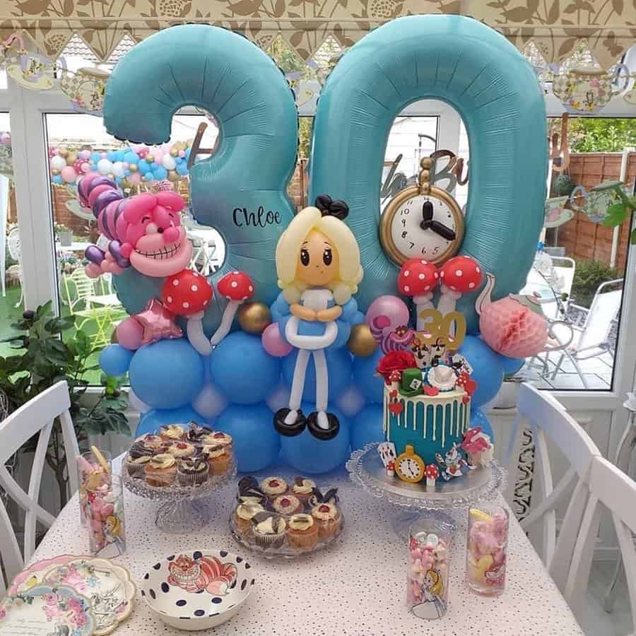 Alice in Wonderland-themed 30th birthday decor with blue balloons and whimsical desserts.