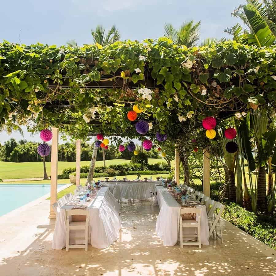 Brunch outdoor birthday party with decorated pergola, white tables, and colorful hanging lanterns.