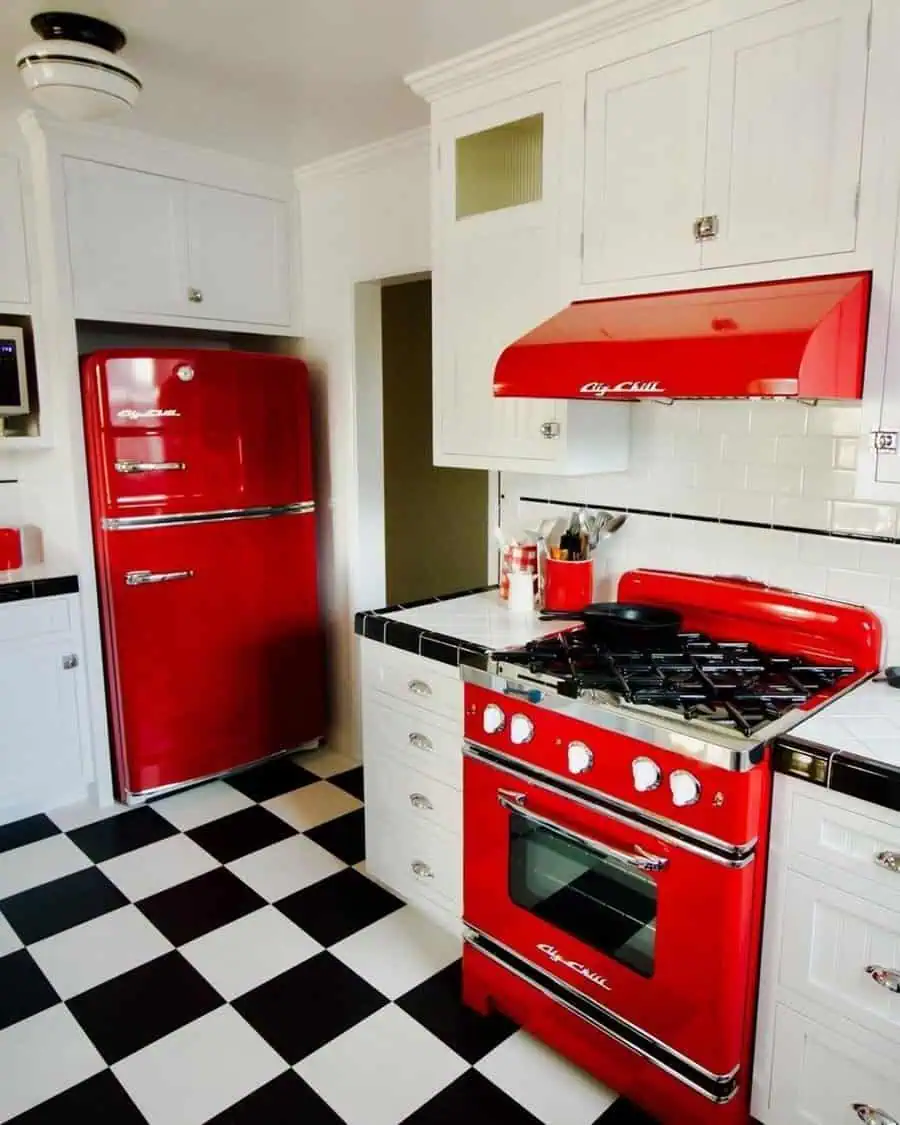 1950s kitchen featuring a bright red retro fridge and oven, glossy white tiles, and a checkered floor.