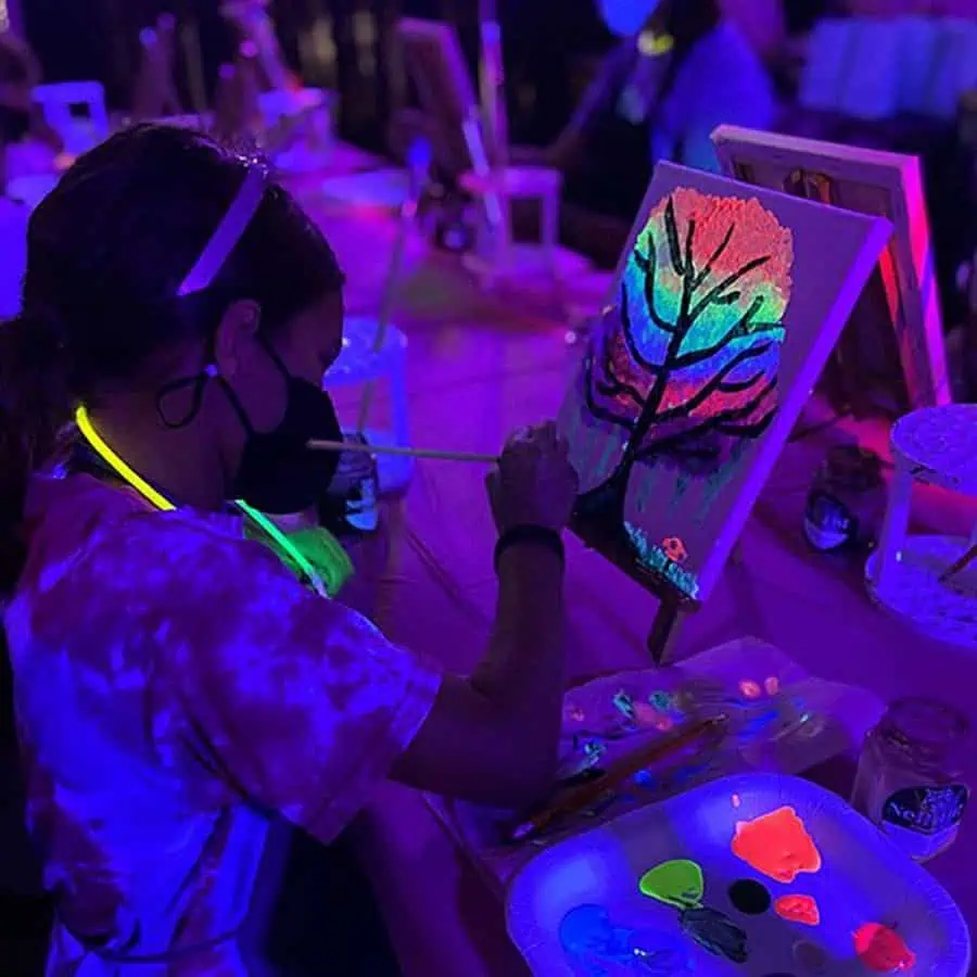 Glow-in-the-dark painting activity at a birthday party with vibrant neon colors.