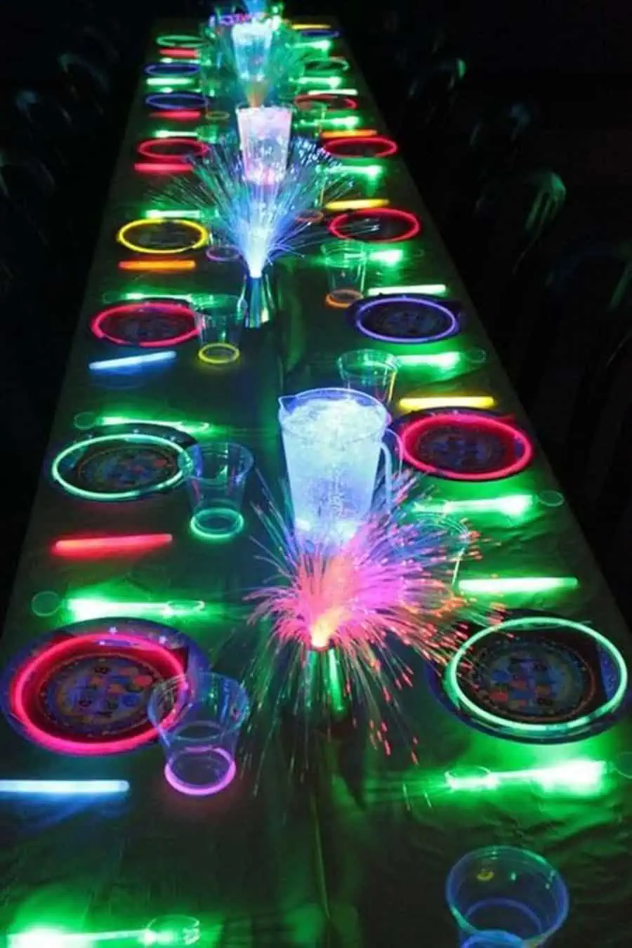 Glow-in-the-dark birthday party table setup with neon lights and vibrant decorations.