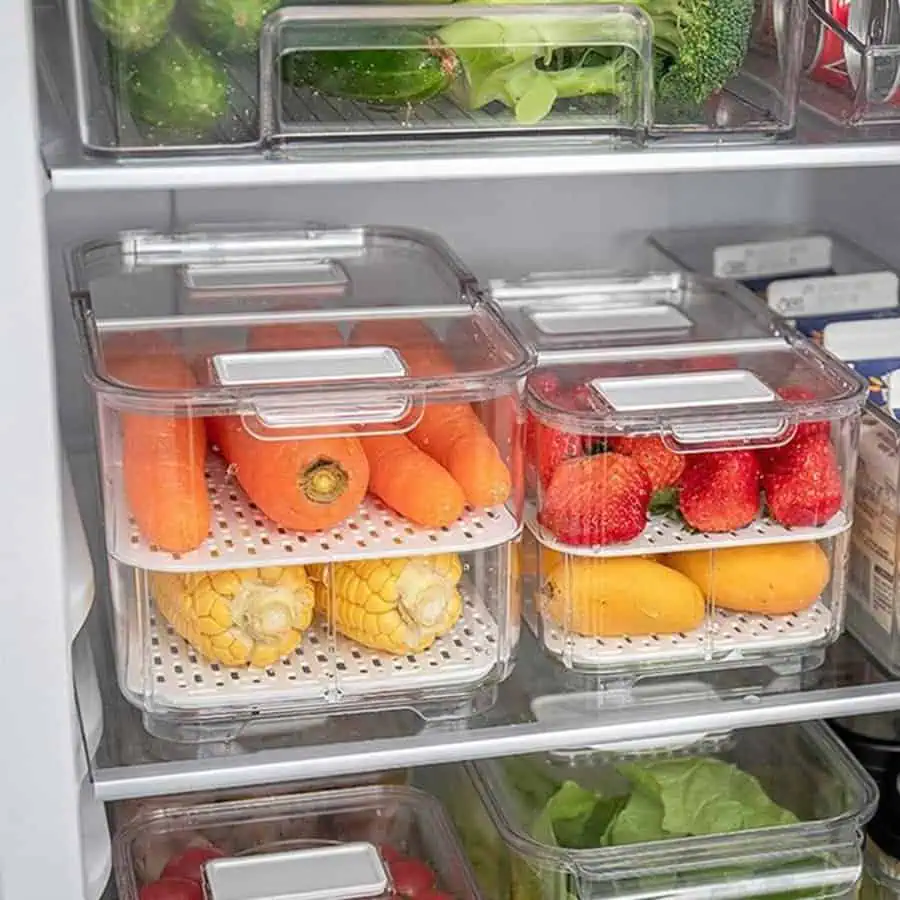 Fresh fruits and vegetables stored in clear, stackable refrigerator containers.