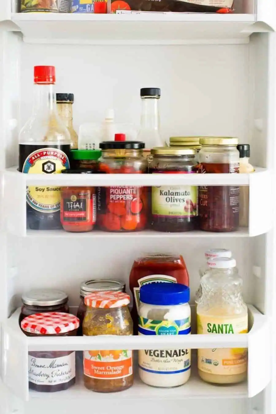 Condiments, sauces, and jars neatly organized in refrigerator door shelves.