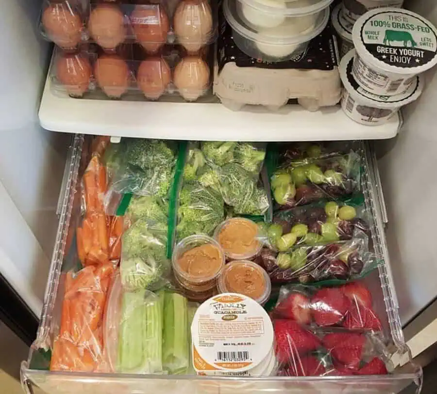 Eggs, yogurt, and fresh fruits and vegetables neatly organized in refrigerator drawers.