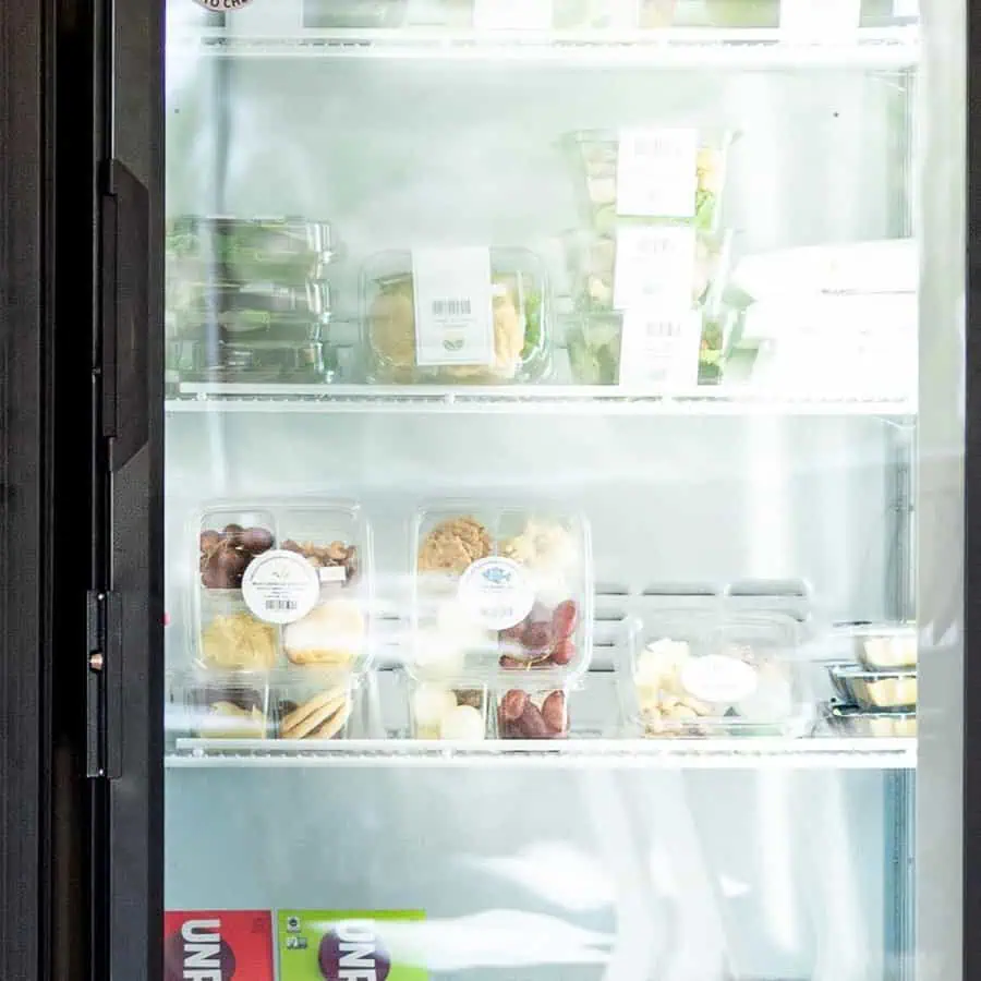 Packaged salads and snacks displayed in a glass-door refrigerator.