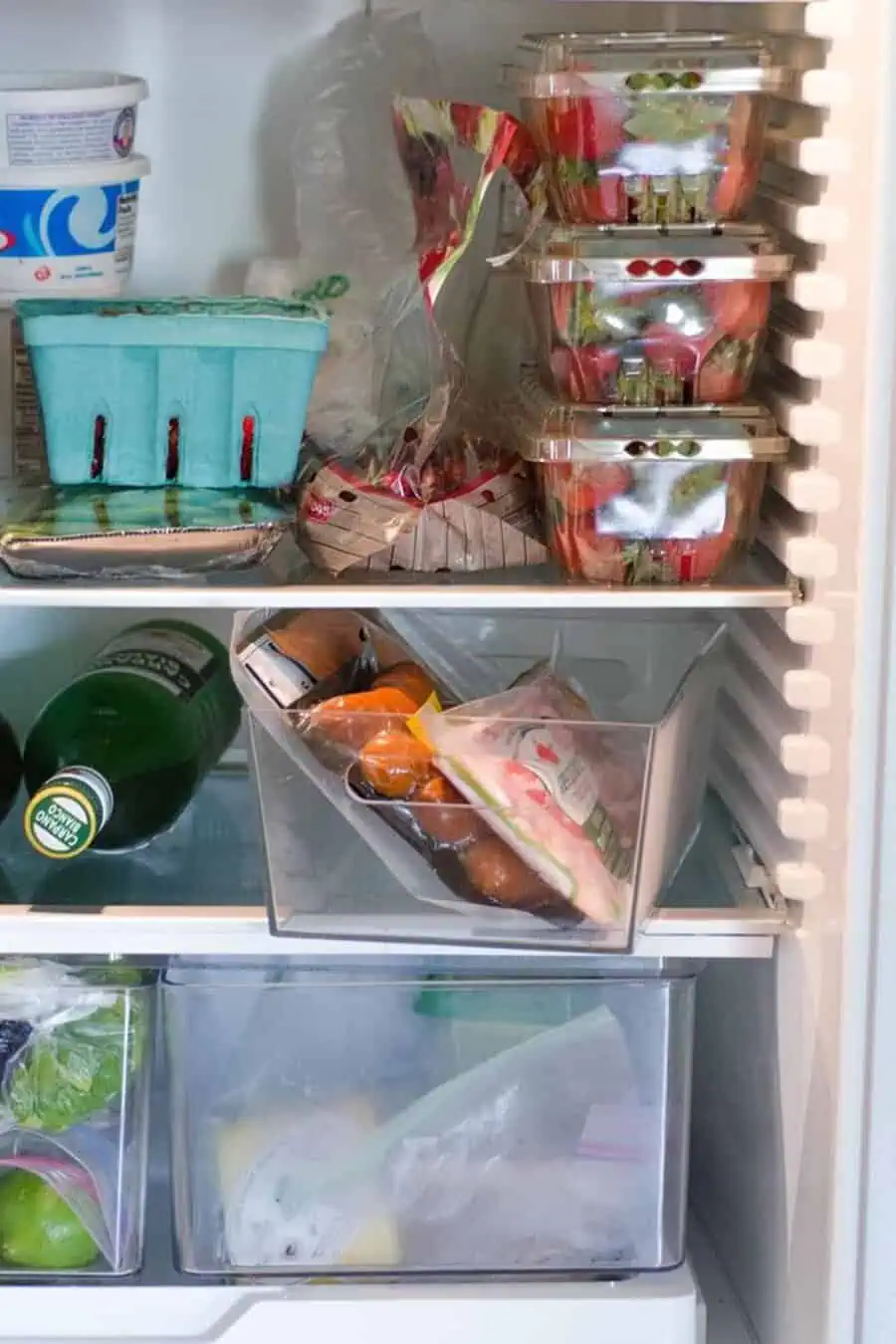 Containers of strawberries, yogurt, and packaged food stored neatly in a refrigerator.